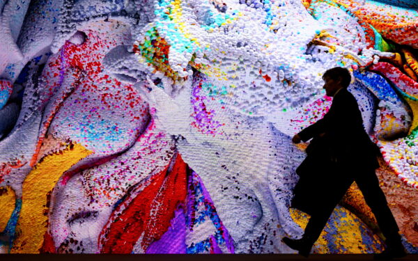 epa11077118 A person walks in front of a screen displaying artificial intelligence (AI) generated artwork by Turkish-American media artist Refik Anadol inside the Congress Center on the eve of the 54th annual meeting of the World Economic Forum (WEF) in Davos, Switzerland, 14 January 2024. The meeting brings together entrepreneurs, scientists, corporate and political leaders in Davos under the topic 'Rebuilding Trust' from 15 to 19 January.  EPA/LAURENT GILLIERON