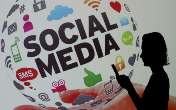 epa10243036 A woman checks her phone next to a screen showing social media icons, in Istanbul, Turkey, 14 October 2022. Turkey's Parliament on 13 October approved a new law proposed by President Recep Tayyip Erdogan that could sentence journalists and social media users to up to three years in prison on charges of spreading disinformation. The law reads that those who spread false information online about Turkey's security in order to 'create fear and disturb public order' can face a prison sentence of up to three years.  EPA/SEDAT SUNA