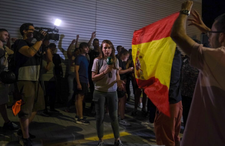 epa12240279 A reporter works next to demonstrators in the town of Torre Pacheco, Murcia, southeastern Spain, late 15 July 2025 (issued 16 July 2025). Spanish security forces banned an anti-migration rally to avoid riots. Unrest in Torre Pacheco, which left several people injured and resulted in multiple arrests, was sparked by an assault on a 68-year-old resident, allegedly by migrants, according to authorities. The incident led to three days of violence in the town, which has a population of approximately 40,000 and a large Maghrebi immigrant community.  EPA/PABLO MIRANZO