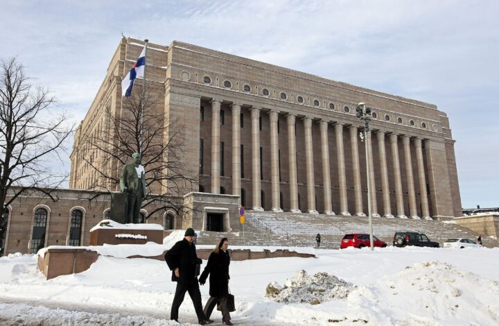 Cidadãos finlandeses passam em frente ao seu parlamento em Helsínquia, Finlândia. TIAGO PETINGA/LUSA